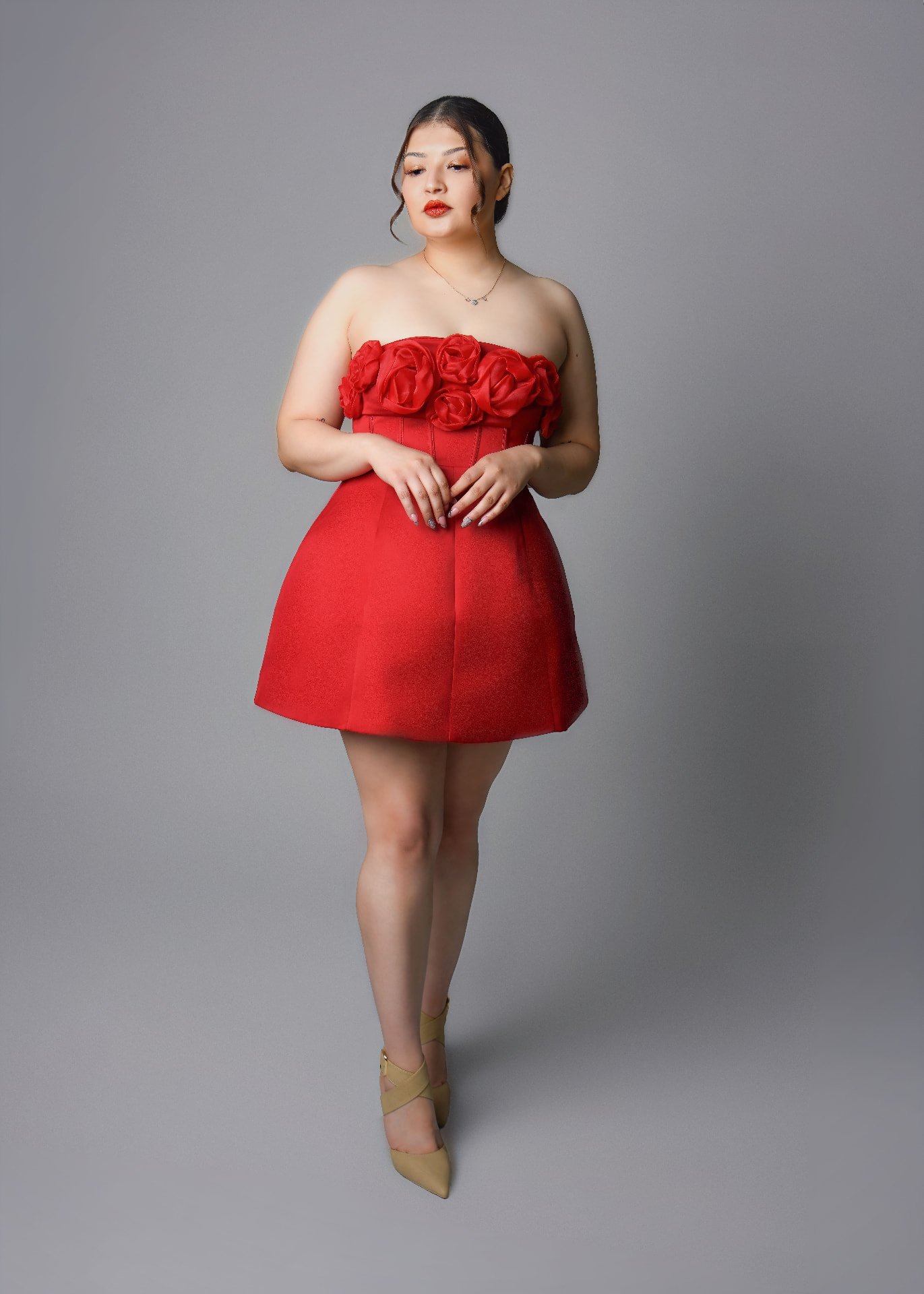 Woman in a red rosette dress standing in a studio birthday portrait